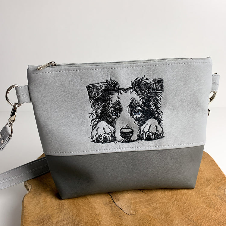 Handgefertigte Tasche mit Hundemotiv, die ein Border Collie-Motiv zeigt. Die Tasche ist zweifarbig unterteilt aus Kunstleder. Der obere Teil ist bestickt.