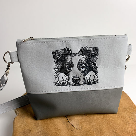 Handgefertigte Tasche mit Hundemotiv, die ein Border Collie-Motiv zeigt. Die Tasche ist zweifarbig unterteilt aus Kunstleder. Der obere Teil ist bestickt.
