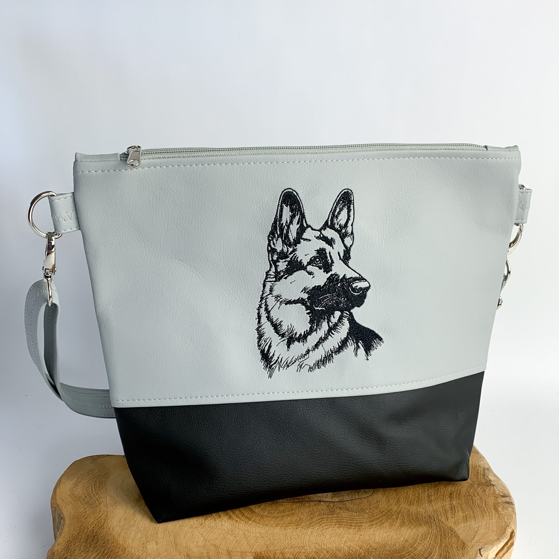 handgefertigte Umhängetasche mit Schäferhund-Motiv bestickt, aus Kunstleder, zweifarbig unterteilt, oben hellgrau, unten schwarz, Motiv schwarz auf hellgrau gestickt als detailreiche Silhouette.