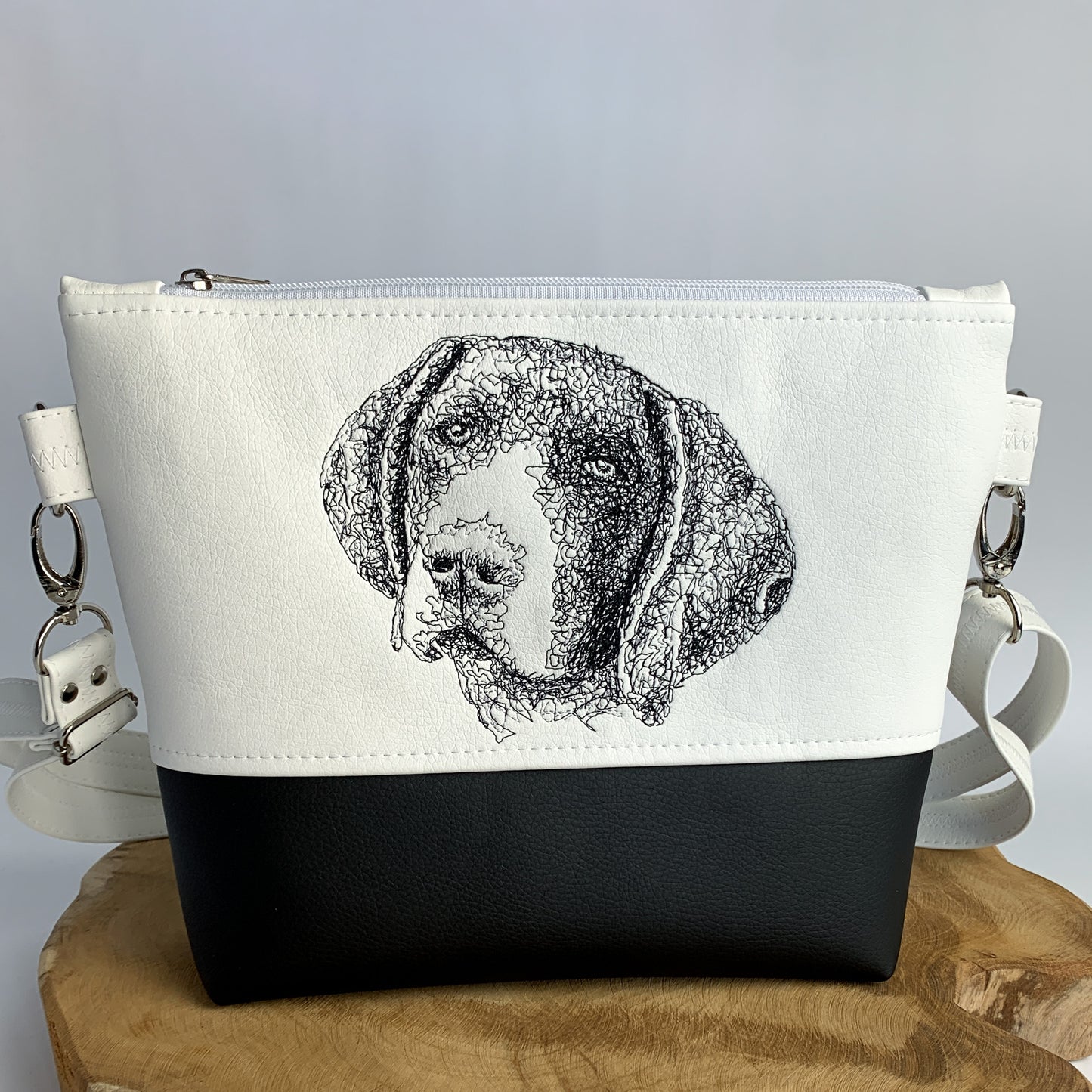 Umhängetasche aus Kunstleder mit Deutsch Kurzhaar-Motiv bestickt, zweifarbig, oben weiß mit schwarzem Stickmotiv (Kopf Deutsch Kurzhaar), unten schwarz.