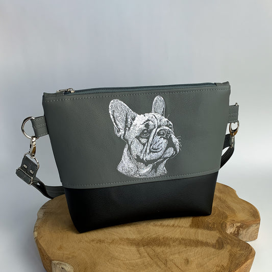 Umhängetasche mit dem Kopf einer Französischen Bulldogge bestickt, handgefertigt aus Kunstleder, zweifarbig, oben dunkelgrau, unten schwarz. das Motiv ist in weiß gestickt und sehr detailreich.